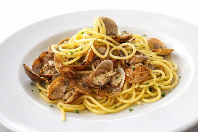 Plate of spaghetti alle vongole with fresh local clams and parsley, a signature dish at Trattoria Locanda Stella in Monti, Sardinia.