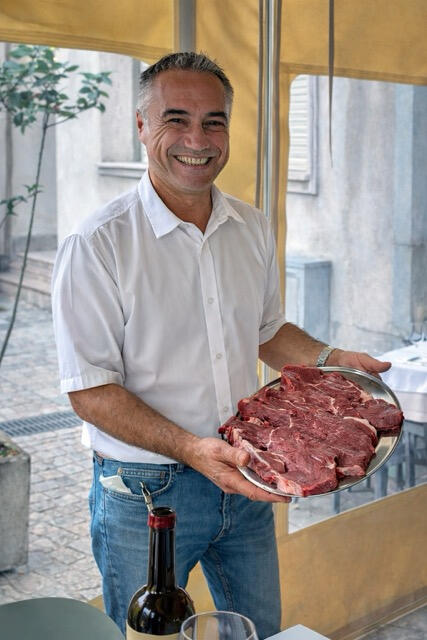 Valerio Presenting Fresh Local Sardinian Meat at Trattoria Locanda Stella, Monti Valerio showing a wooden plateau plate of fresh local Sardinian meat at Trattoria Locanda Stella in Monti, Sardinia.